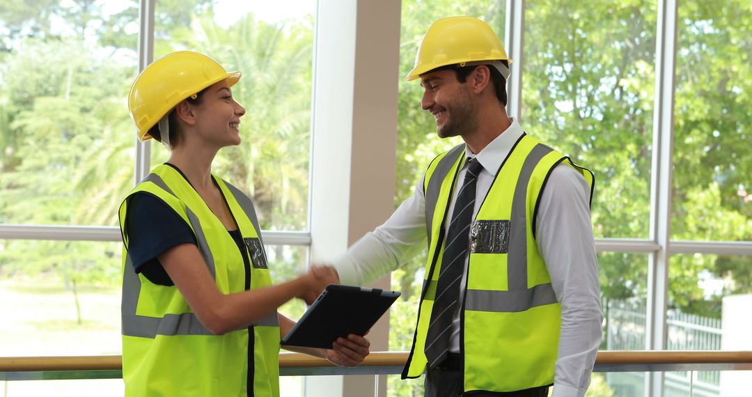 Two professionals in construction gear are shaking hands, likely over project discussions. - Free Images, Stock Photos and Pictures on Pikwizard.com