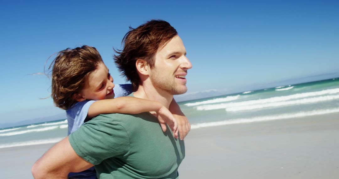 Father giving piggyback ride to son on beach - Free Images, Stock Photos and Pictures on Pikwizard.com