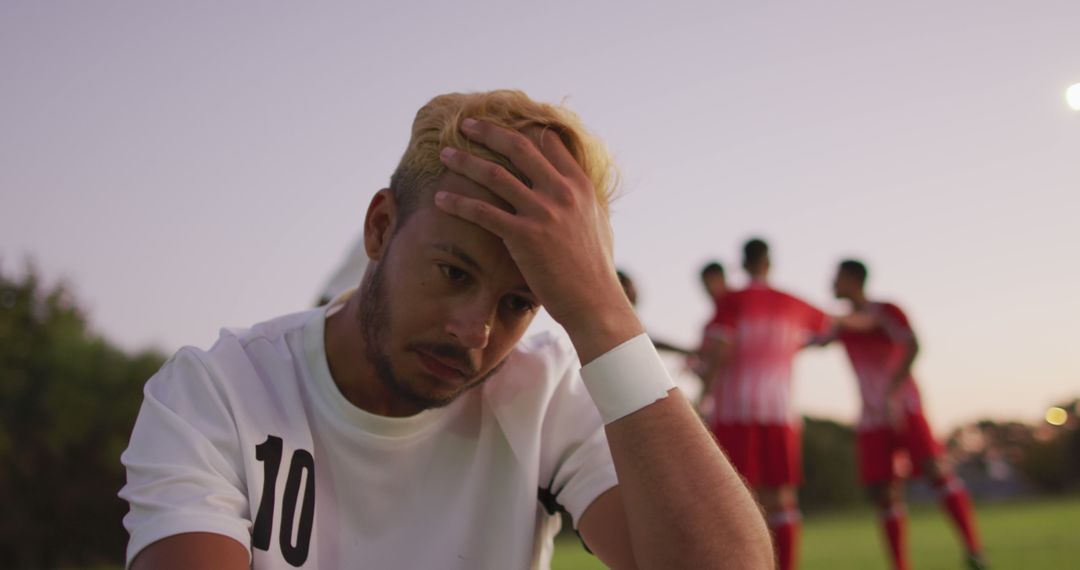 Disappointed Soccer Player Reacting to Loss While Teammates Discuss - Free Images, Stock Photos and Pictures on Pikwizard.com