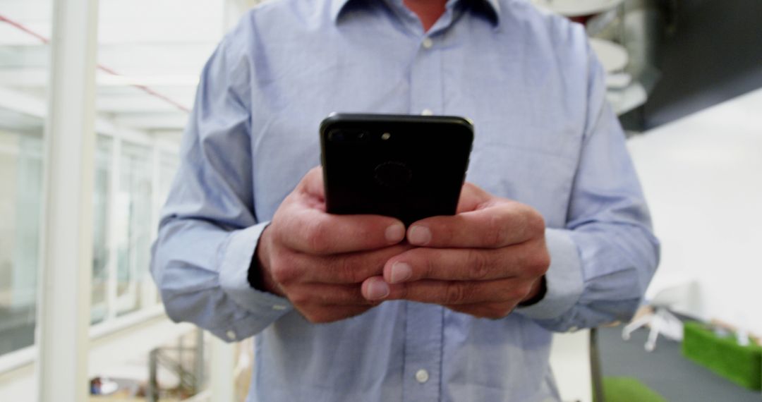 Casual Businessman Checking Smartphone in Modern Office