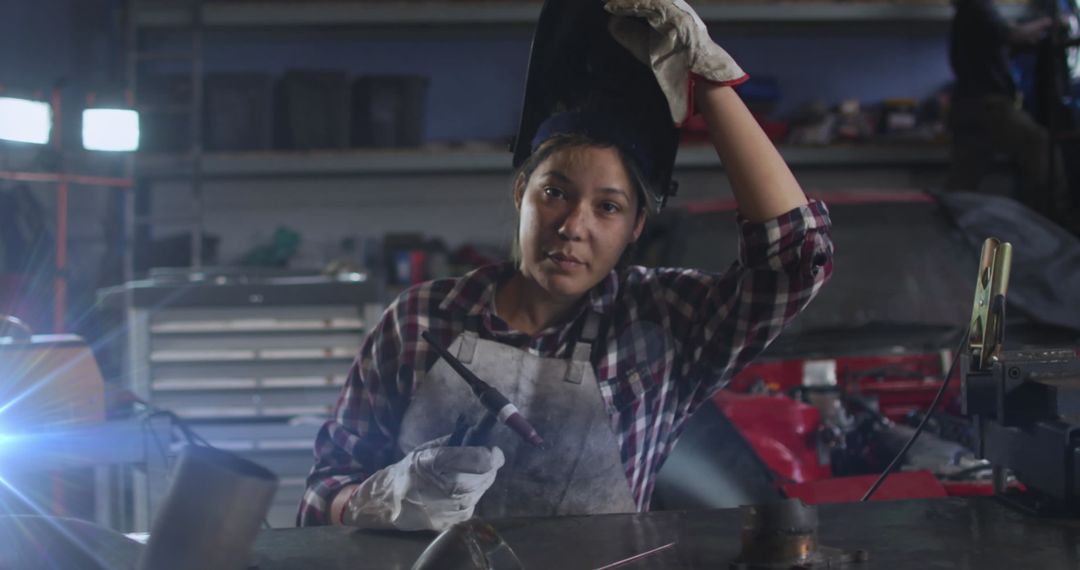 Young Woman Welding in Workshop with Determined Expression