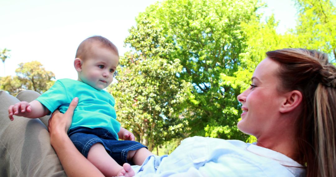 Smiling Mother Holding Baby in Park on Sunny Day - Free Images, Stock Photos and Pictures on Pikwizard.com