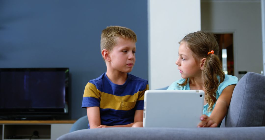 Two Children Sitting on Couch Interacting with Digital Tablet - Free Images, Stock Photos and Pictures on Pikwizard.com