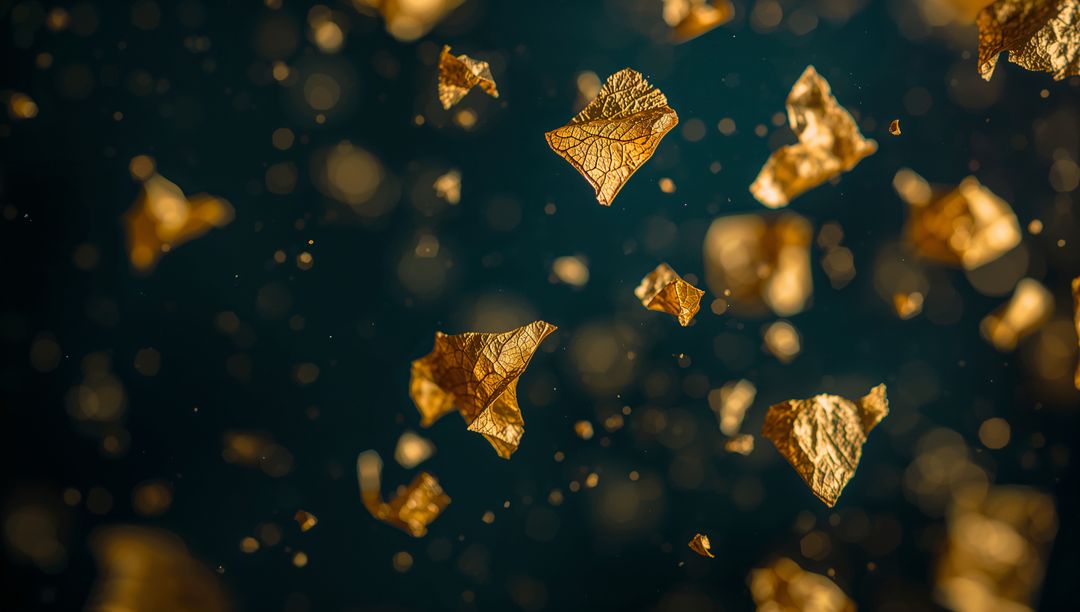 Drifting golden leaf flakes glinting over dark teal backdrop with dusty bokeh orbs