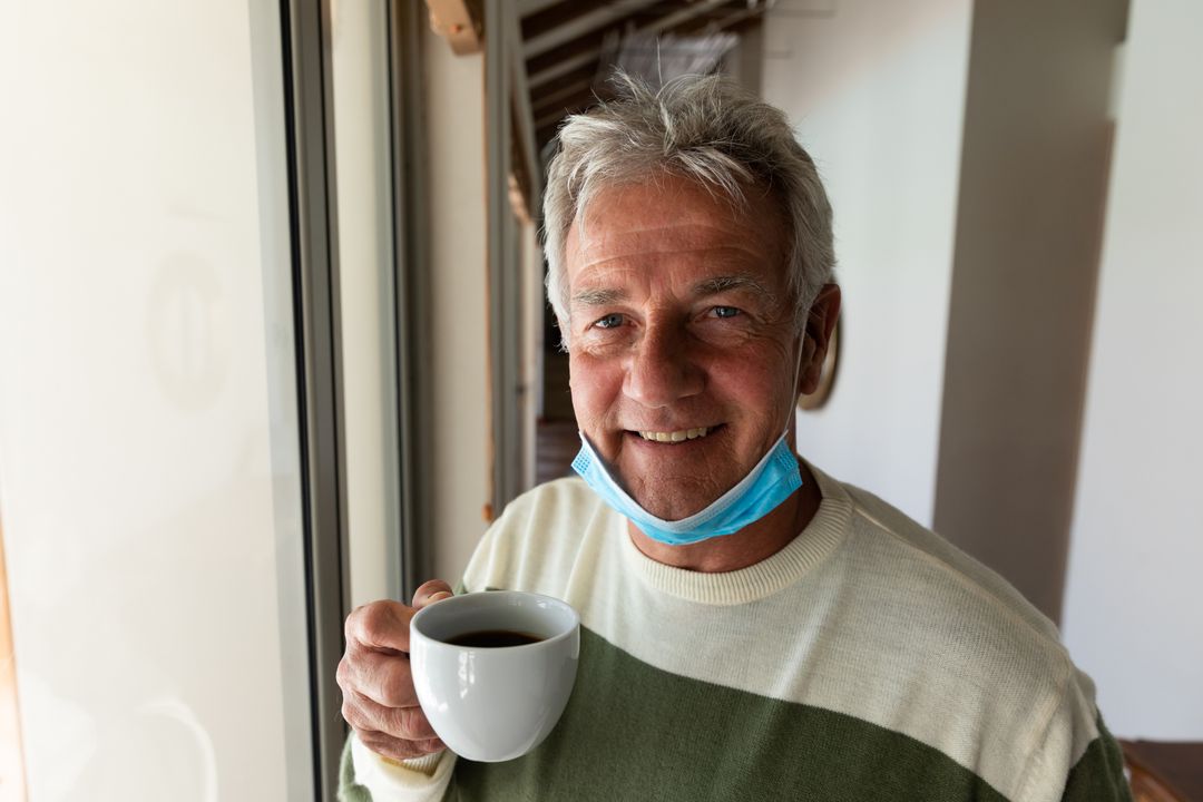 Senior Man with Lowered Face Mask Holding Coffee Cup at Home - Free Images, Stock Photos and Pictures on Pikwizard.com