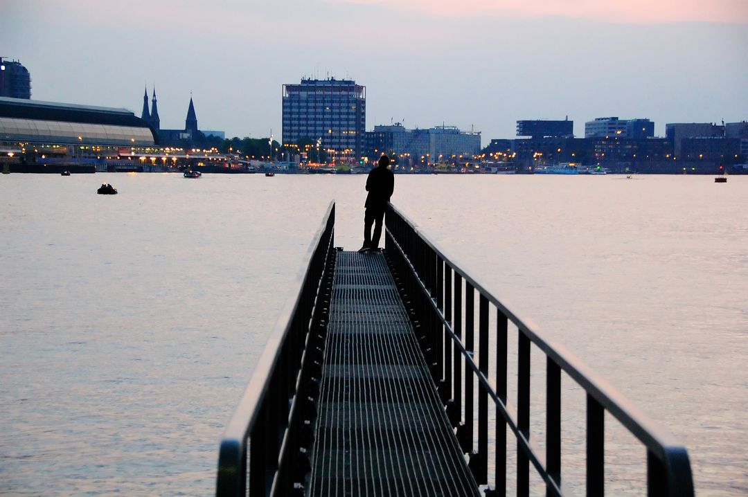 Silhouette of Lovers Embracing on Waterfront Pier at Dusk