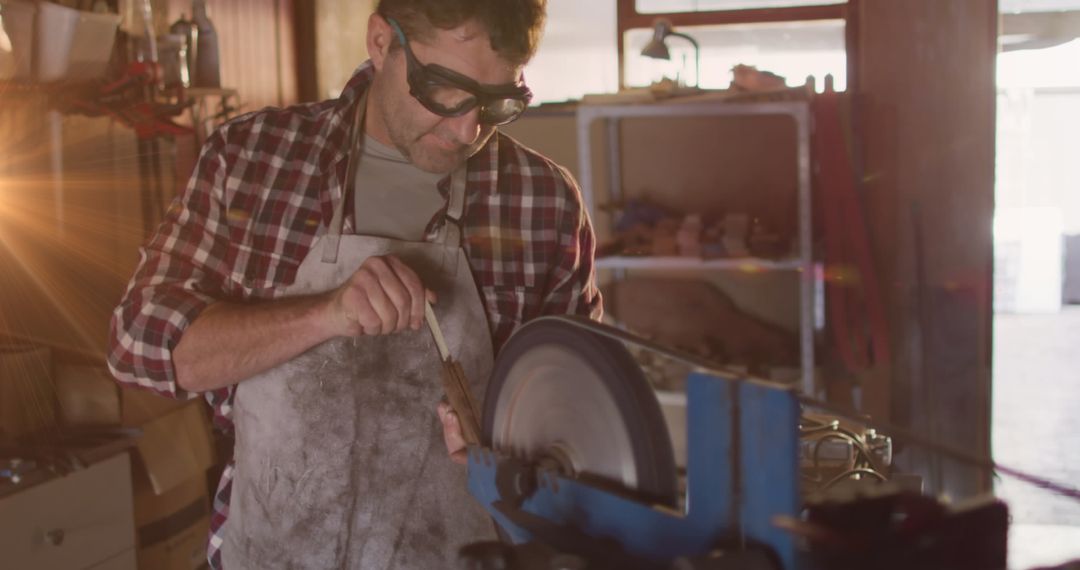 Craftsman Using Grinding Wheel in Workshop with Glowing Light