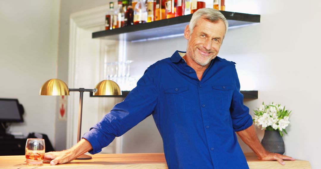 Smiling Mature Man with Drink at Bar Counter