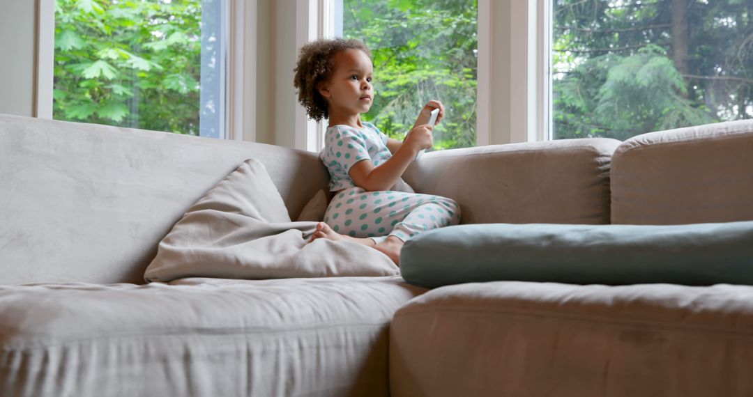 Child with Curly Hair Relaxing on Couch by Window - Free Images, Stock Photos and Pictures on Pikwizard.com