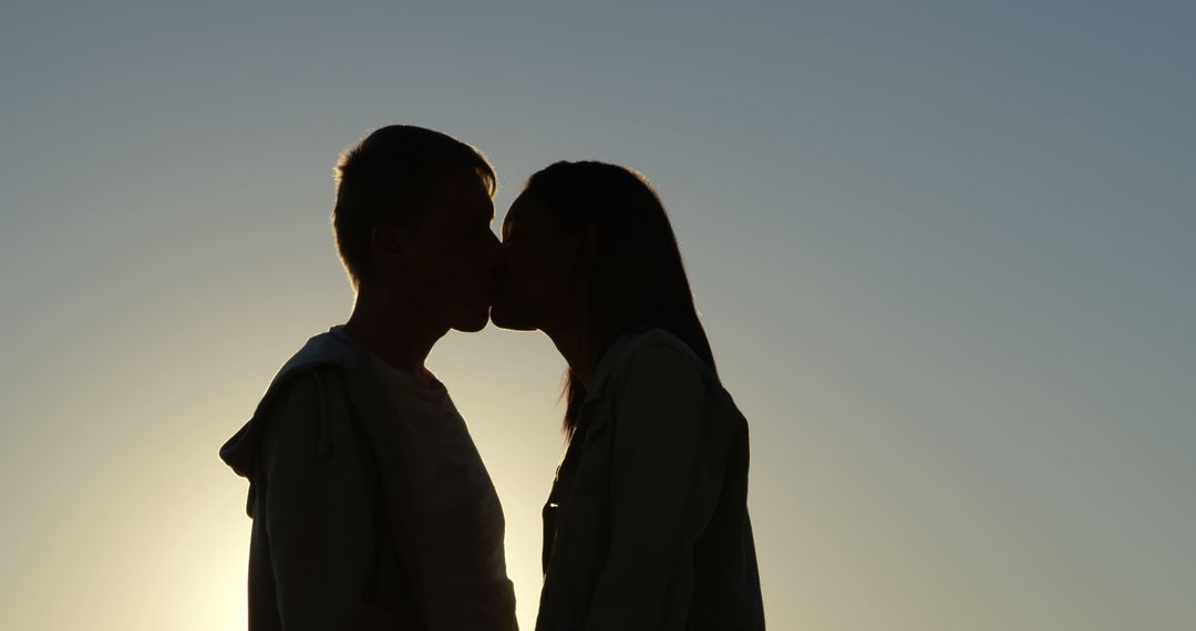 Silhouetted against a serene sky, a young Caucasian couple shares a romantic kiss, with copy space - Free Images, Stock Photos and Pictures on Pikwizard.com