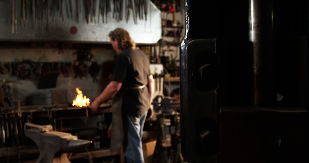 Blacksmith Working in Dimly Lit Workshop with Glowing Forge - Free Images, Stock Photos and Pictures on Pikwizard.com