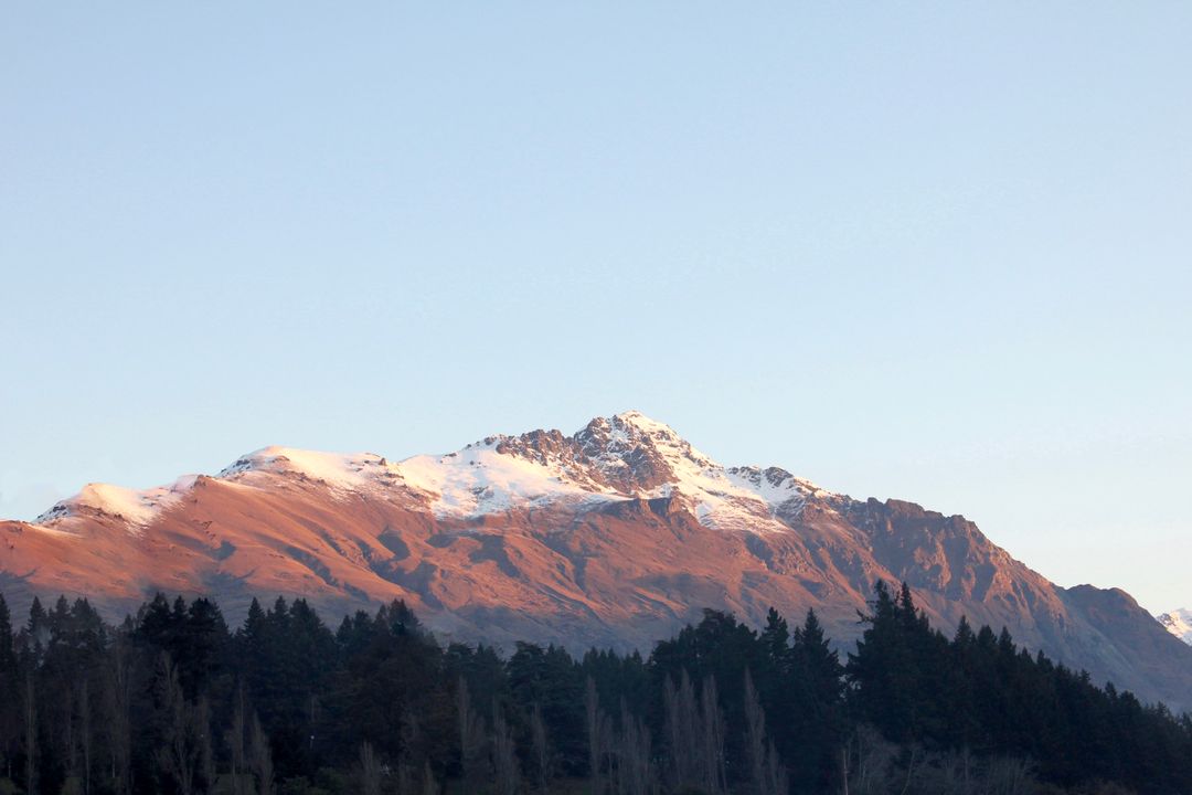 Sunrise Illuminating Snow-Capped Mountain Peak with Forest View - Free Images, Stock Photos and Pictures on Pikwizard.com