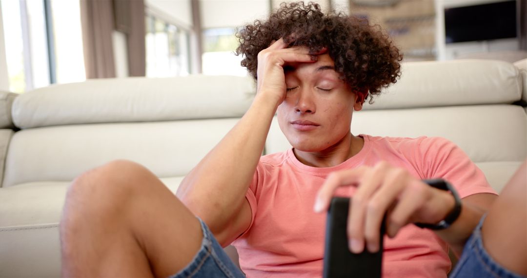 Stressed Young Man Relaxing on Couch Holding Remote