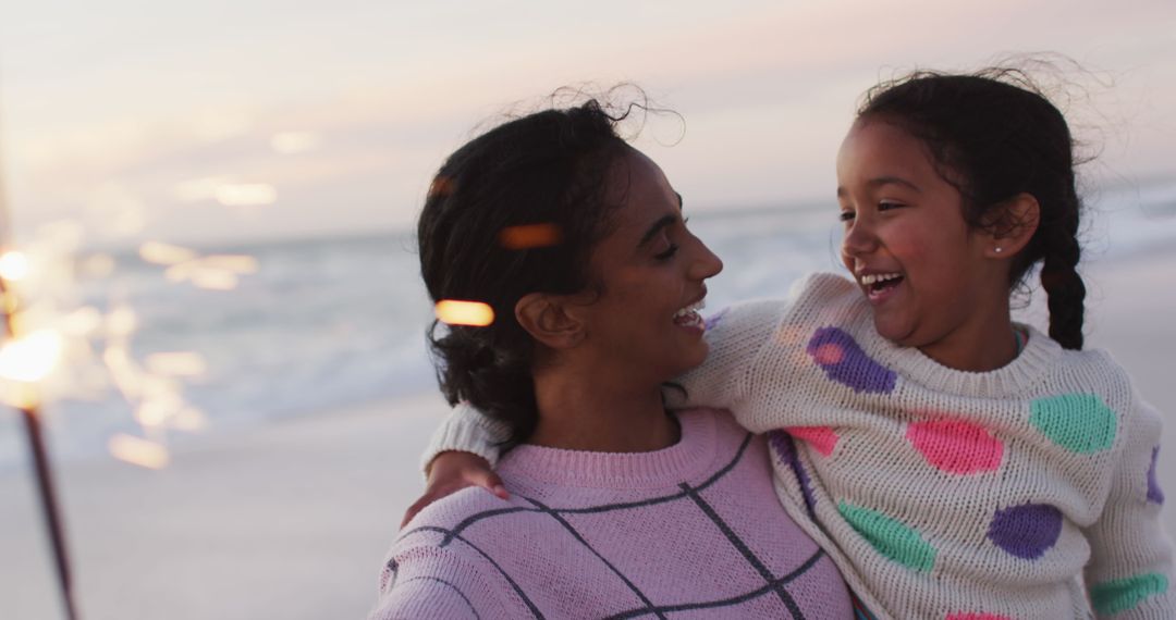 Happy Mother and Daughter Enjoying Sparklers at Sunset Beach