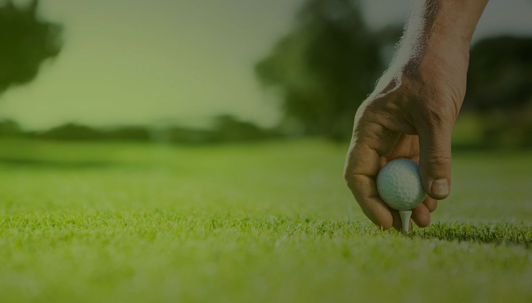 Close-up of Hand Placing Golf Ball on Tee in Scenic Field