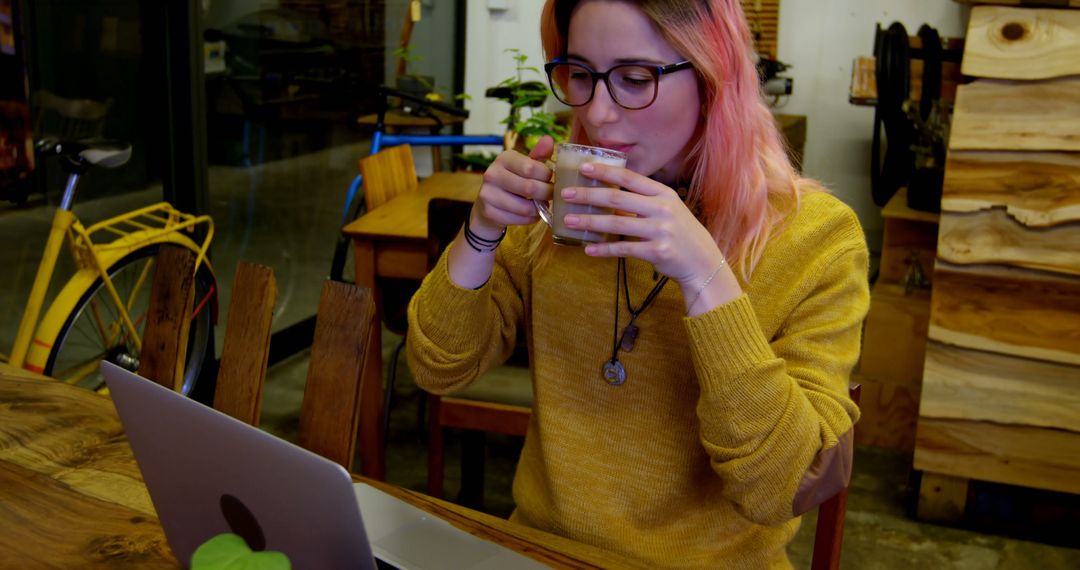 Young Woman with Pink Hair Working on Laptop While Drinking Coffee at Cozy Cafe - Free Images, Stock Photos and Pictures on Pikwizard.com