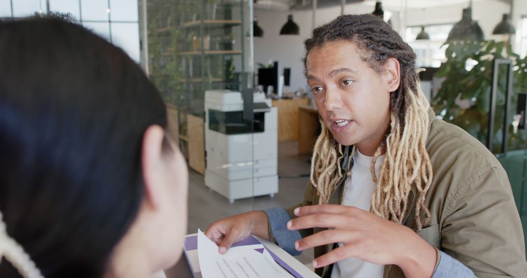 Young Man with Dreadlocks Discussing Document in Modern Office - Free Images, Stock Photos and Pictures on Pikwizard.com