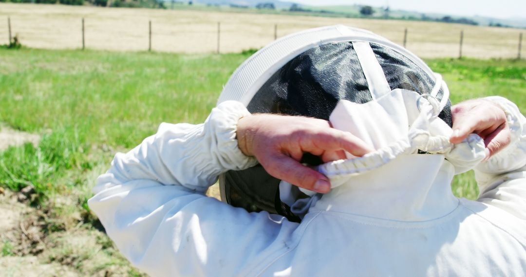 Beekeeper Donning Suit for Harvest in Rural Apiary