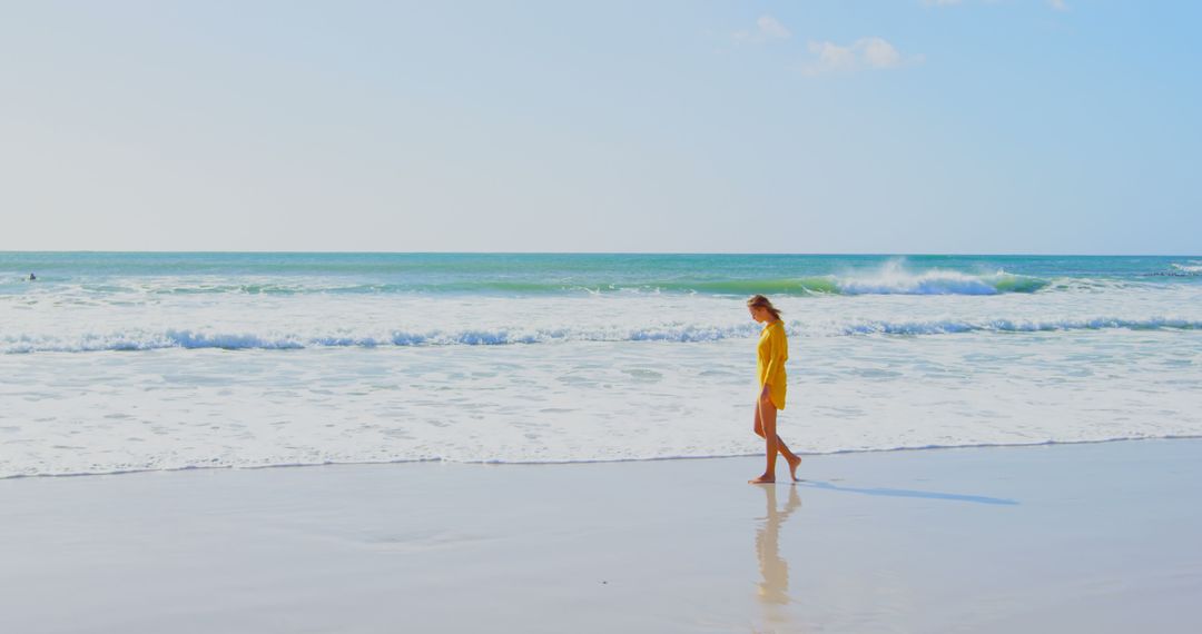 Woman in Yellow Dress Walking Along Serene Beach - Free Images, Stock Photos and Pictures on Pikwizard.com