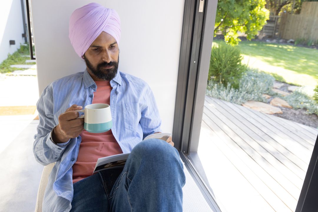 Sikh Man Relaxing with Mug and Smartphone by Window