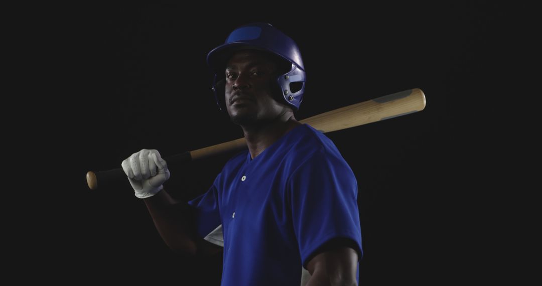 Focused Baseball Player in Blue Jersey Holding Bat Against Dark Background - Free Images, Stock Photos and Pictures on Pikwizard.com