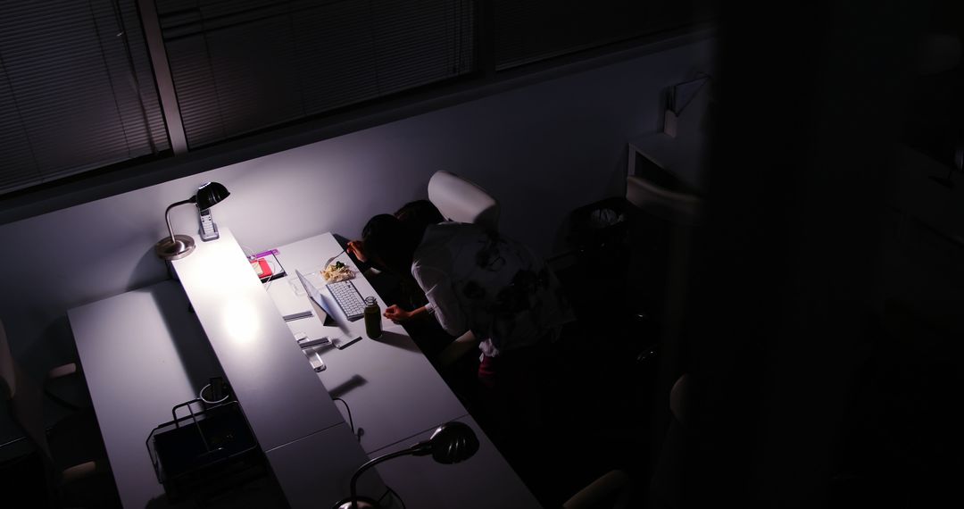 Person Working Late Night in Office Illuminated by Desk Lamp - Free Images, Stock Photos and Pictures on Pikwizard.com