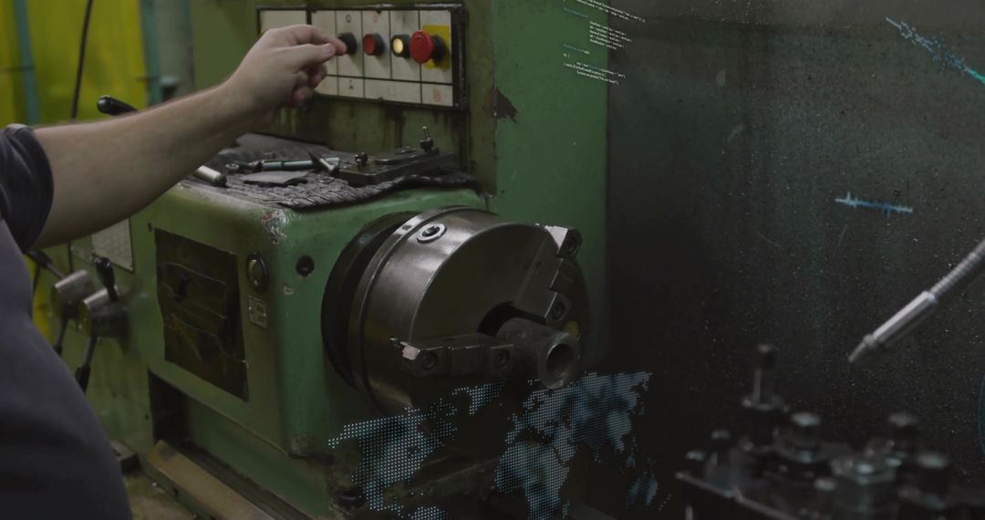 Machinist reaching to press control button on lathe chuck in dim industrial workshop