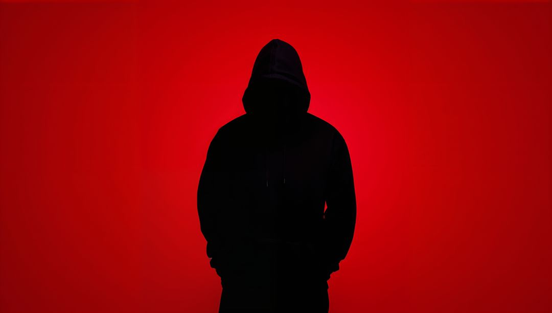 Mysterious Hooded Figure Against Gradient Red Backdrop
