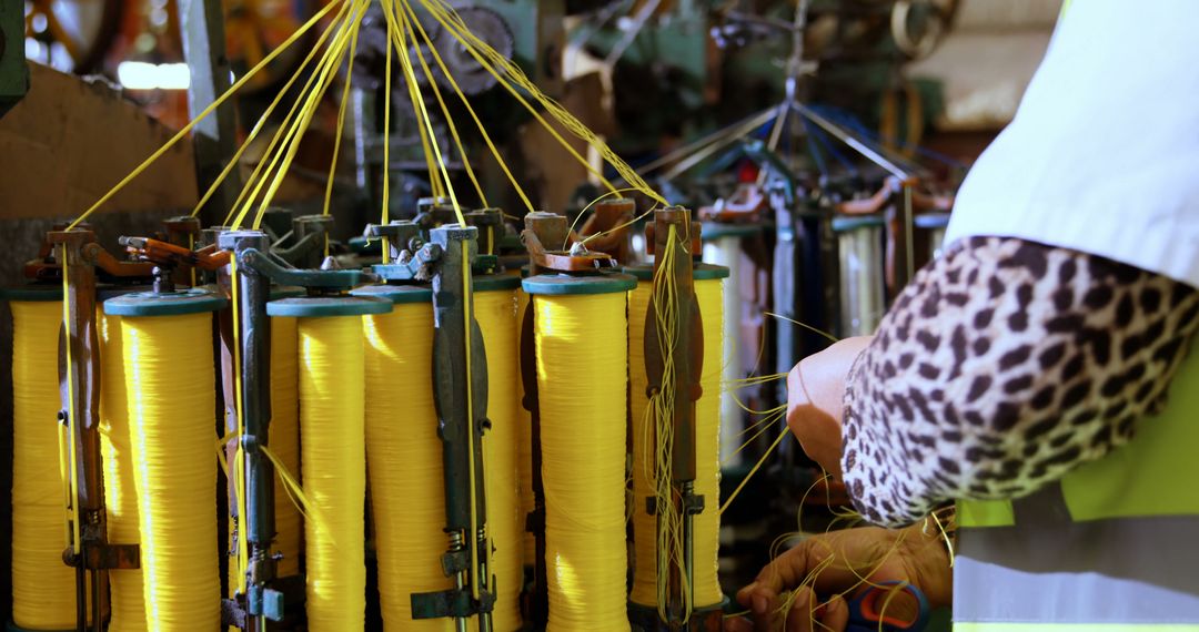 Factory worker operating textile machine with yellow thread spools - Free Images, Stock Photos and Pictures on Pikwizard.com