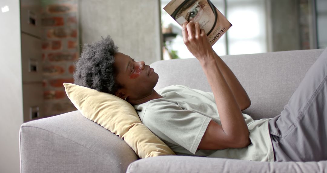 Young Man Relaxing on Couch and Reading Book at Home - Free Images, Stock Photos and Pictures on Pikwizard.com