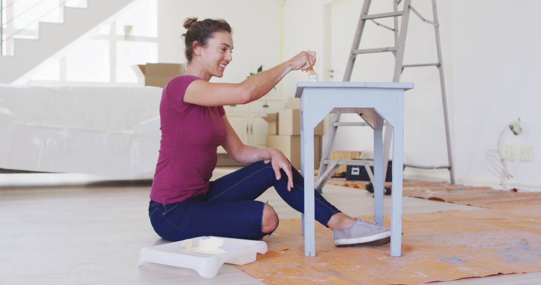 Happy caucasian woman painting wooden table with white paint - Free Images, Stock Photos and Pictures on Pikwizard.com