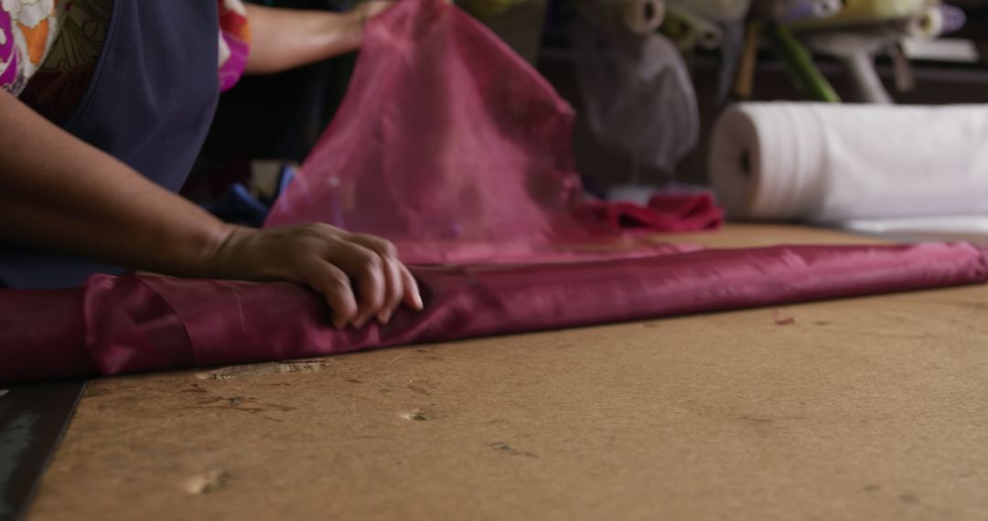 Person Rolling Red Fabric in Workshop - Free Images, Stock Photos and Pictures on Pikwizard.com