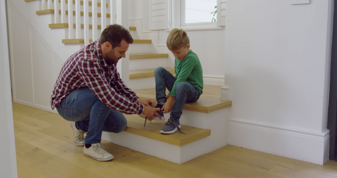 Happy caucasian father with son tying his shoes on stairs at home - Free Images, Stock Photos and Pictures on Pikwizard.com