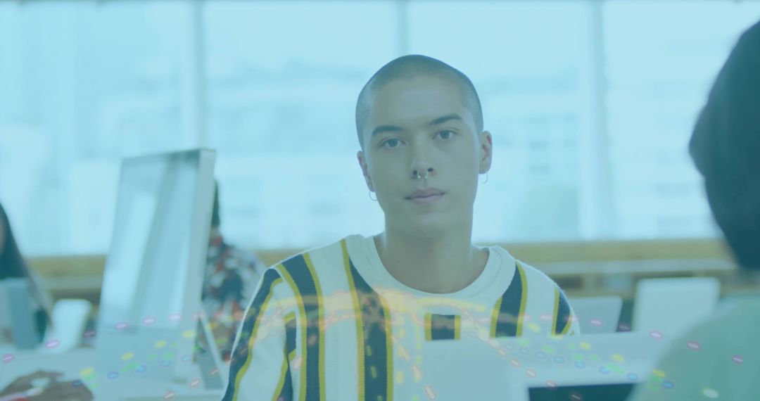 Young professional with shaved head working on laptop in bright open office