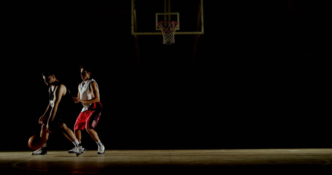 Basketball Players Competing on Basketball Court in Low Lighting - Free Images, Stock Photos and Pictures on Pikwizard.com