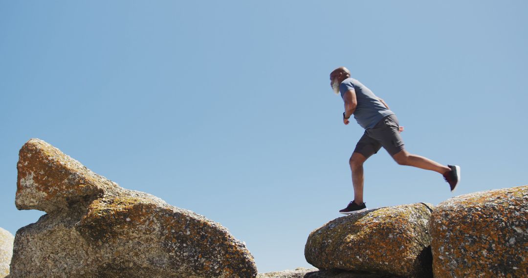 Man Running Over Rocky Formation Against Clear Blue Sky - Free Images, Stock Photos and Pictures on Pikwizard.com