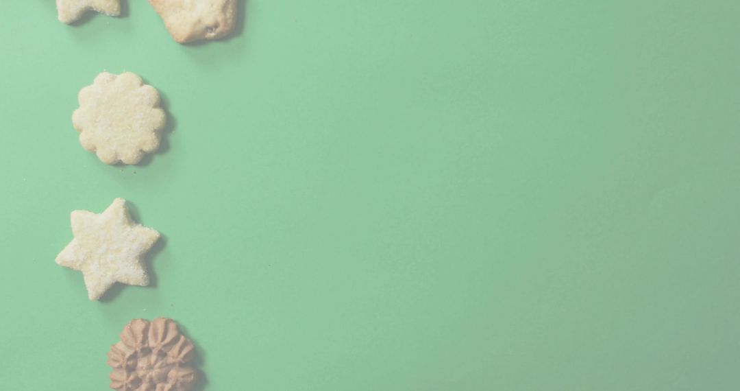 Assorted Sugar-Dusted Cookies Lining Left on Mint Green Backdrop with Plenty of Copy Space