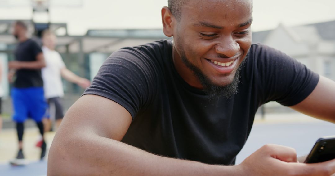 Smiling Basketball Player Using Smartphone on Court