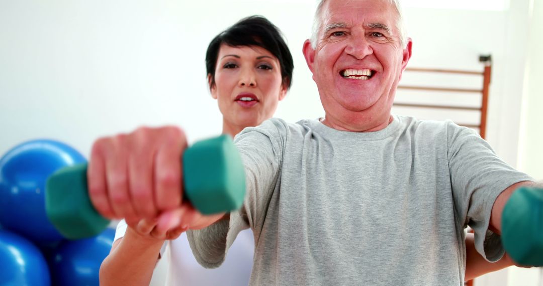 Smiling Senior Man Exercising with Personal Trainer and Dumbbells - Free Images, Stock Photos and Pictures on Pikwizard.com