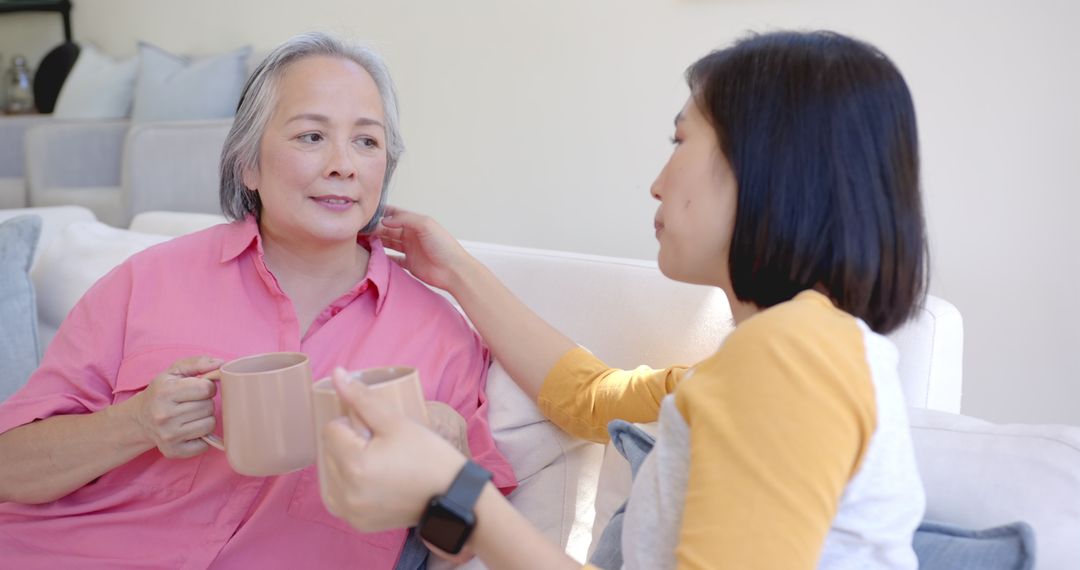 Two Women Enjoying Coffee on Sofa Engaged in Heartfelt Discussion