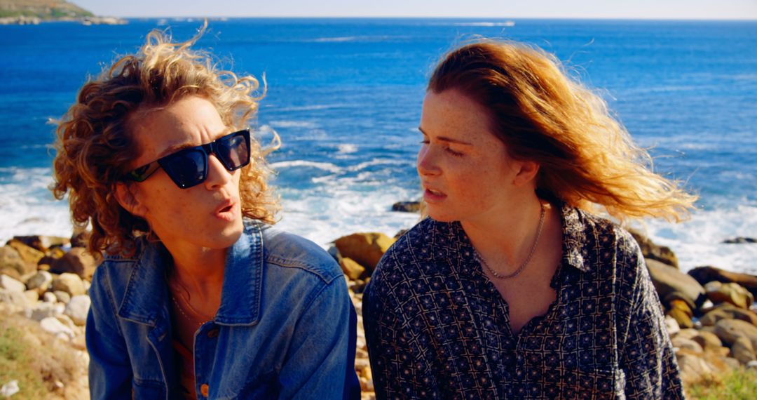 Two Women Talking by Ocean with Rocky Shore - Free Images, Stock Photos and Pictures on Pikwizard.com