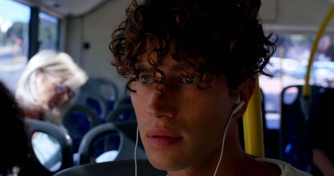 Young Man with Curly Hair Wearing Earphones on Public Bus - Free Images, Stock Photos and Pictures on Pikwizard.com