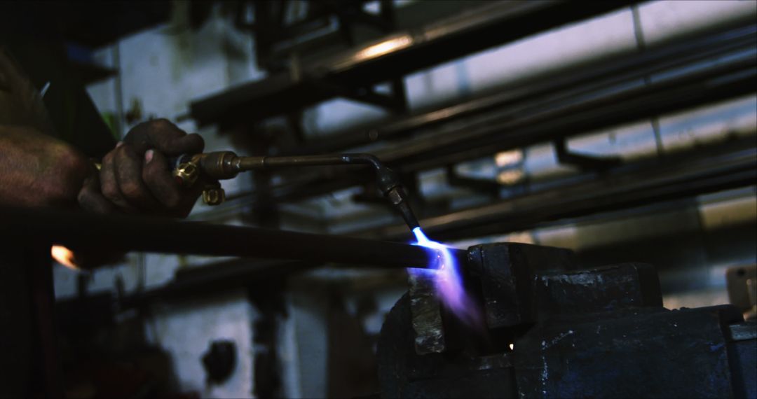 Metalworker using blowtorch on steel rod in industrial workshop - Free Images, Stock Photos and Pictures on Pikwizard.com