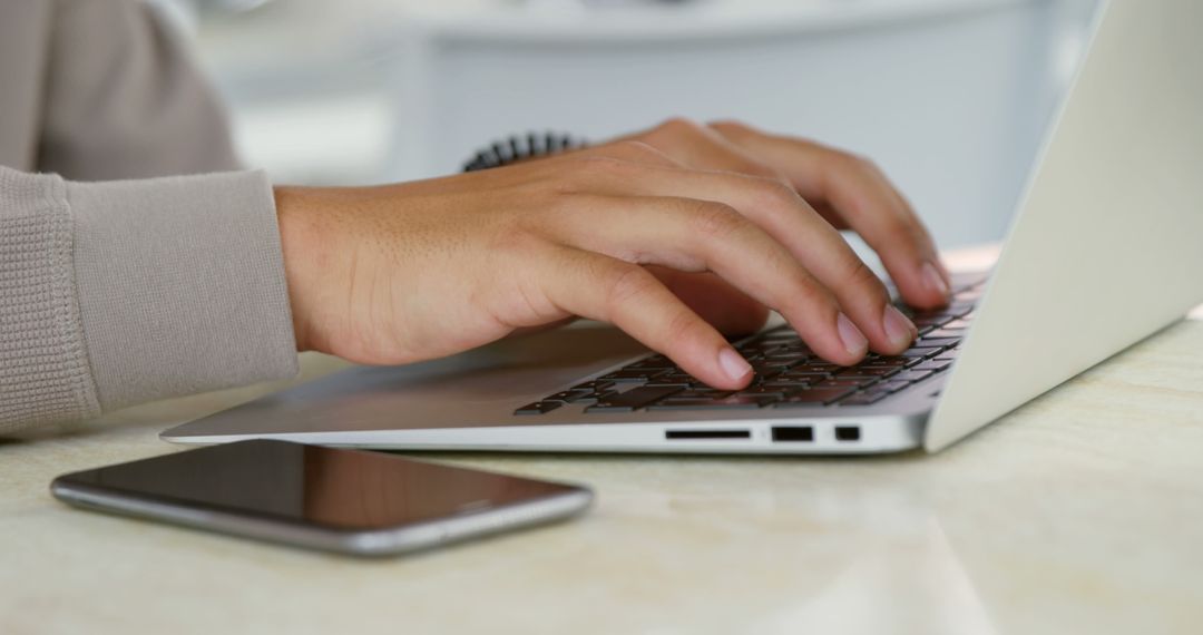 Person Typing on a Laptop with a Smartphone Nearby - Free Images, Stock Photos and Pictures on Pikwizard.com