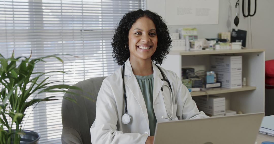 Smiling Female Doctor Working on Laptop in Medical Office - Free Images, Stock Photos and Pictures on Pikwizard.com