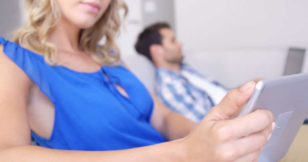 Couple Relaxing with Digital Devices on Sofa at Home