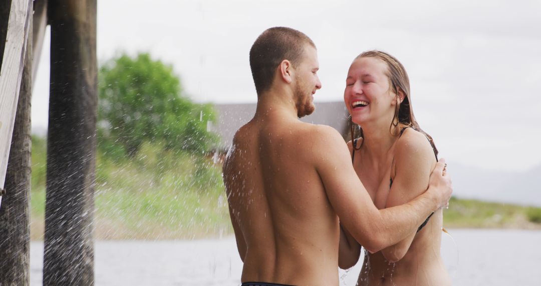 Joyful Couple Enjoying Outdoor Shower by Lake - Free Images, Stock Photos and Pictures on Pikwizard.com