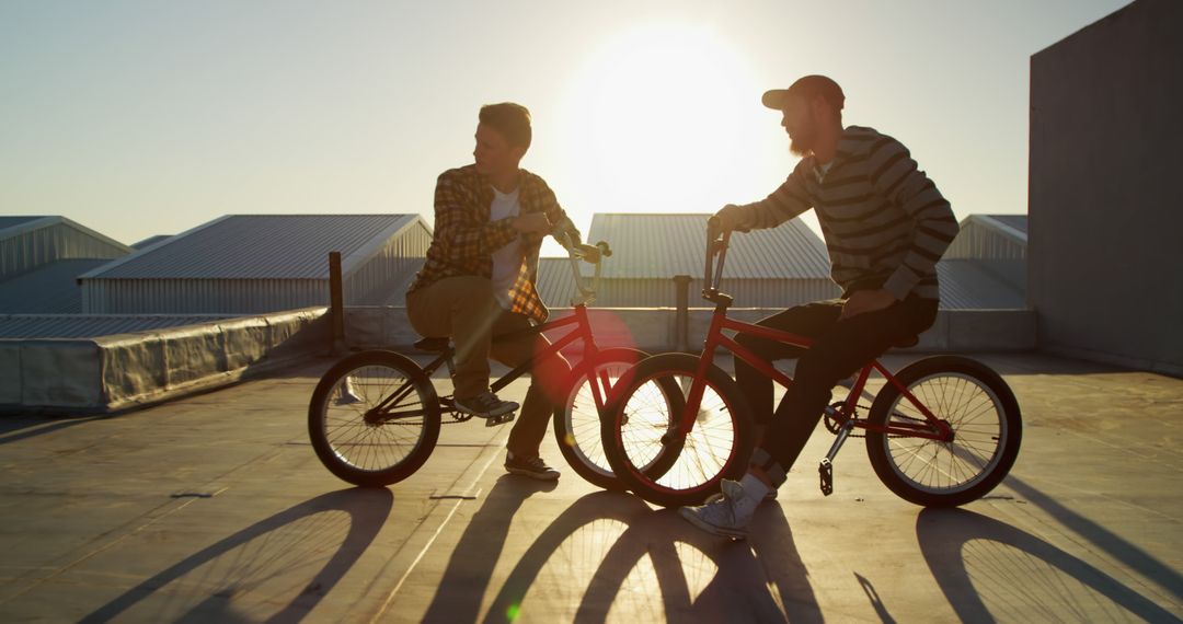 Two Young Men Riding BMX Bikes at Sunset on Rooftop, Silhouetted Scene - Free Images, Stock Photos and Pictures on Pikwizard.com