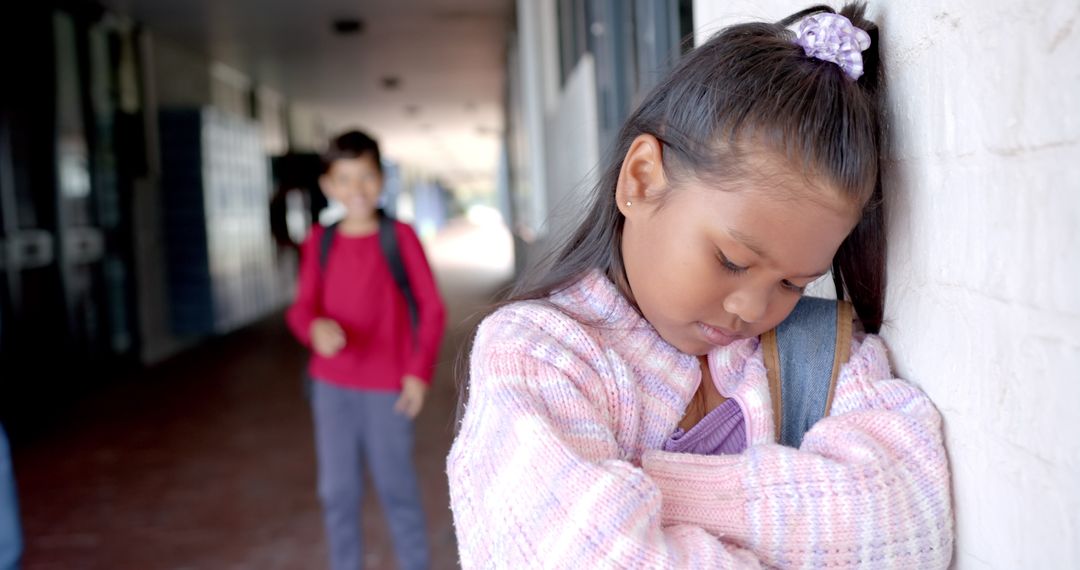Sad Schoolgirl Leaning Against Wall with Boy in Background