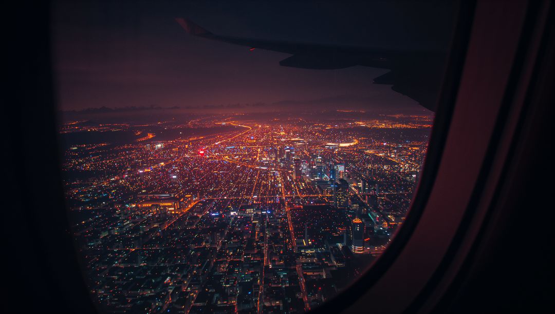 Cityscape Night View from Plane Window with Illuminated Skyline